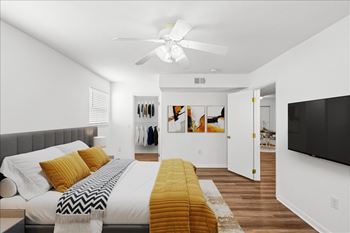 A bedroom with a bed, a ceiling fan, and a clothing rack. at Malvern Hill Apartment Homes, 66103